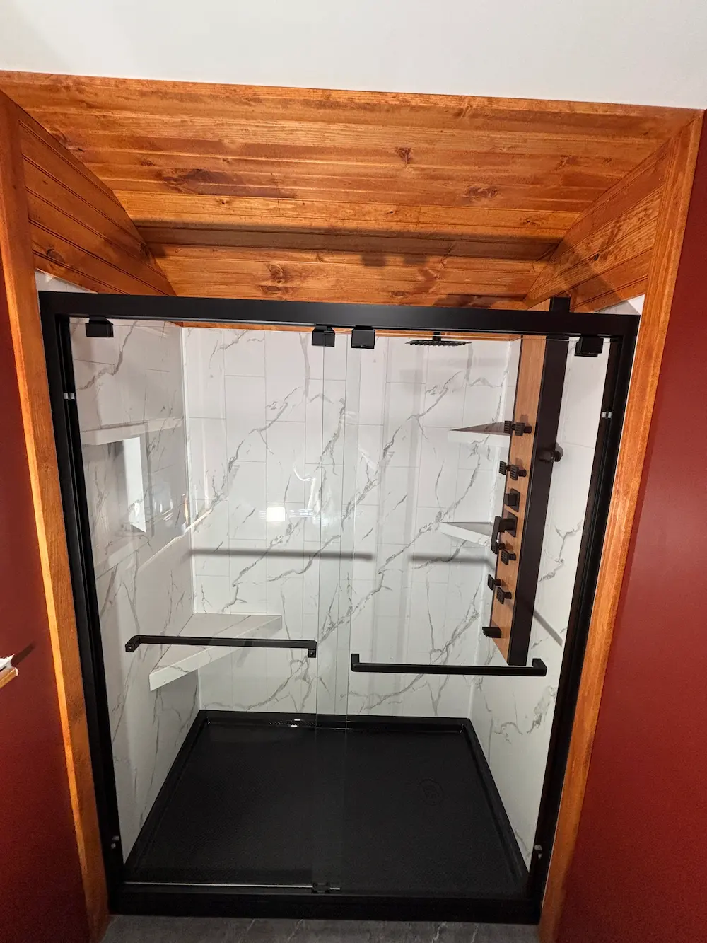 After: Modern walk-in shower with glass doors and marble-style tile